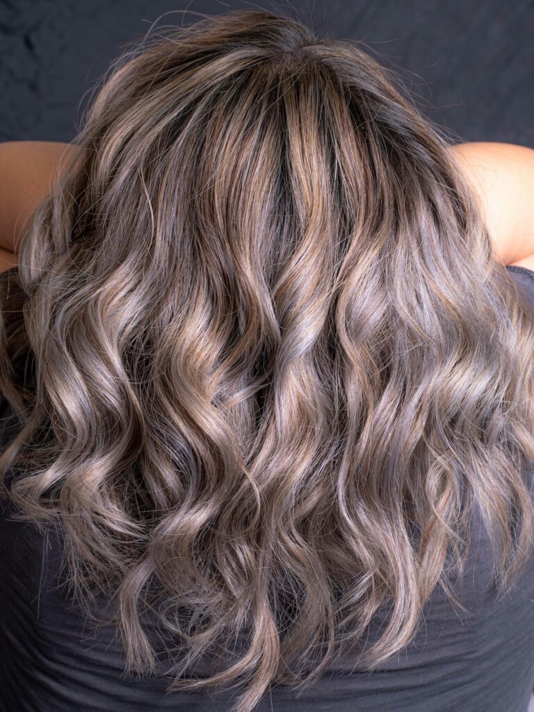 Back of woman’s head showing wavy blended grey hair.