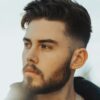 Man standing outside with dark hair featuring a taper fade haircut with a textured top