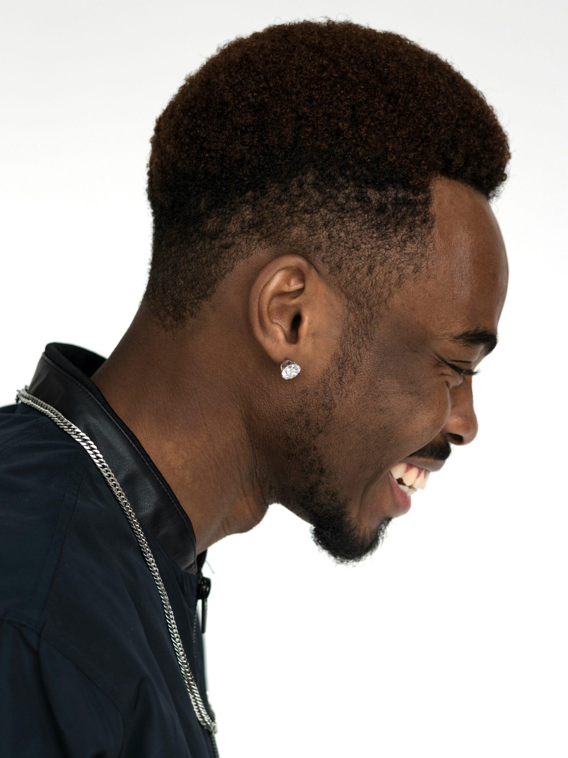 Side profile on a man smiling with afro hair paired with a high taper fade haircut