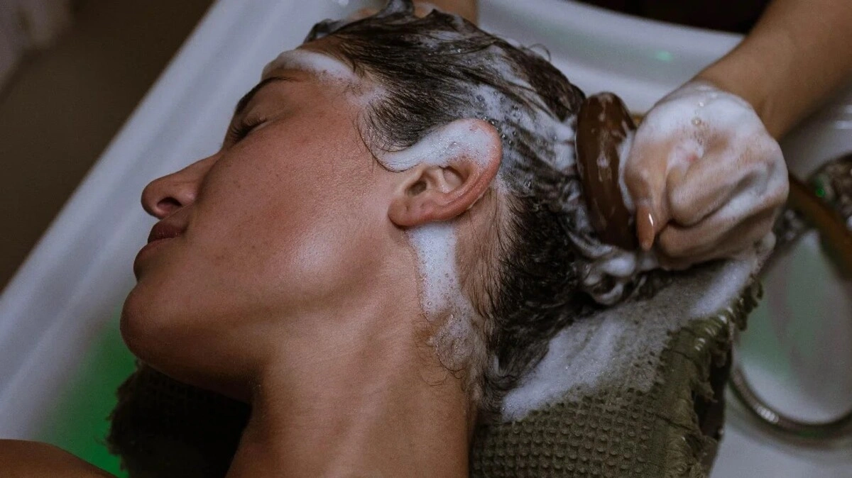 Close-up of a therapist performing a Japanese head spa using a scalp brush on a client