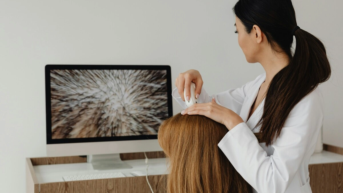 A therapist using a high-resolution camera to view a client’s scalp and showing the image on a big screen