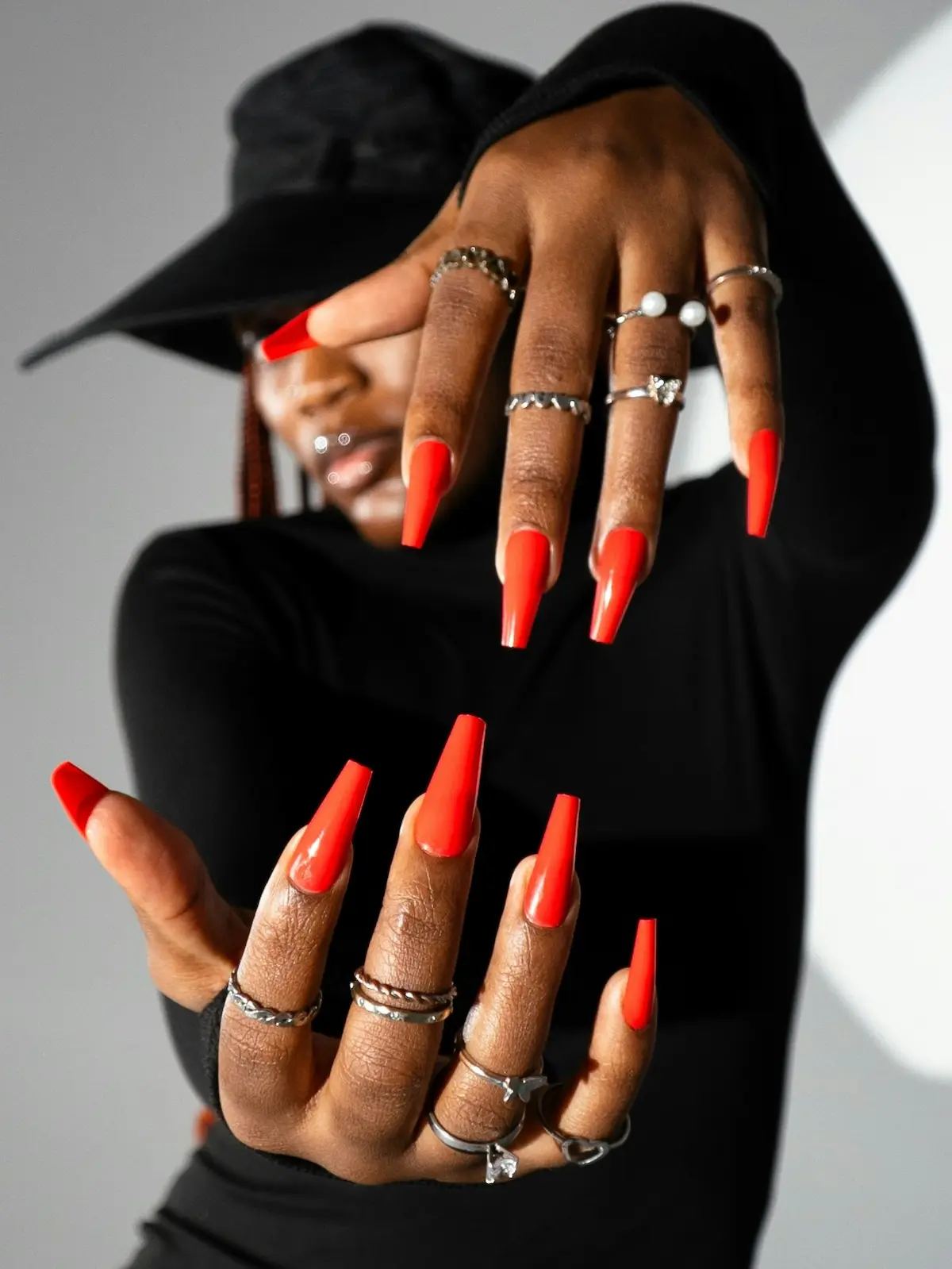 A woman holding her manicured hands in front of the camera showing bright orange coffin-shaped acrylic nails
