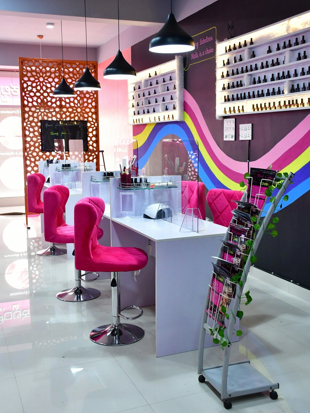 Interior of a nail salon with clean and tidy white desks, pink velvet chairs and a purple wall