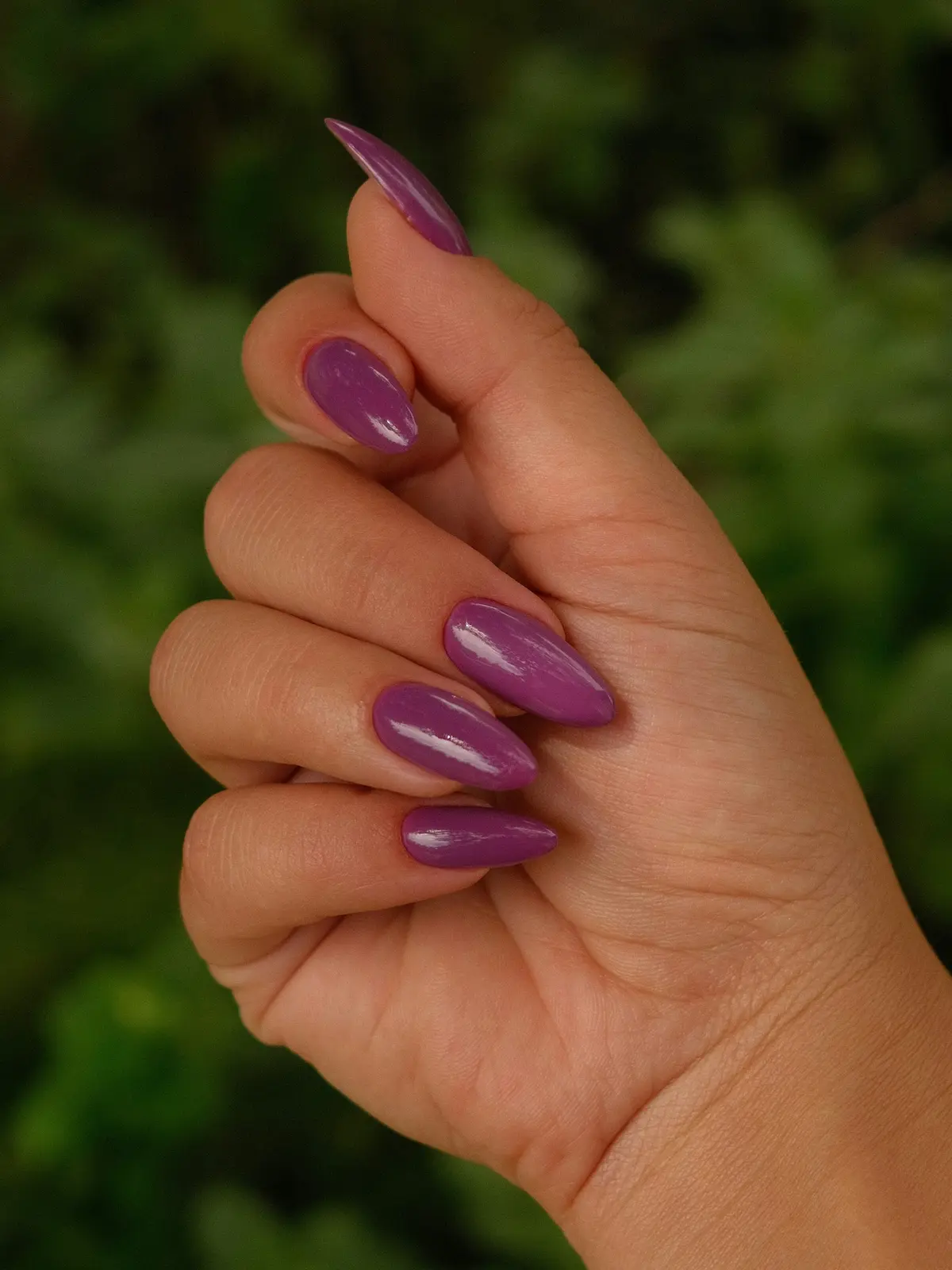 Close-up of a woman’s hand with purple almond-shaped acrylic nails