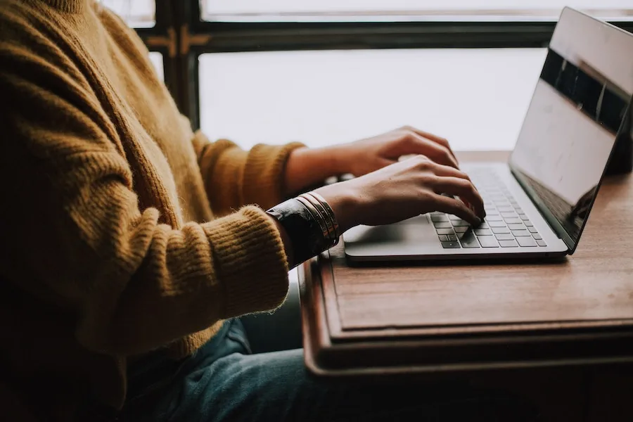 Een saloneigenaar zit aan een tafel en werkt op een laptop om de administratie van haar zaak bij te houden.
