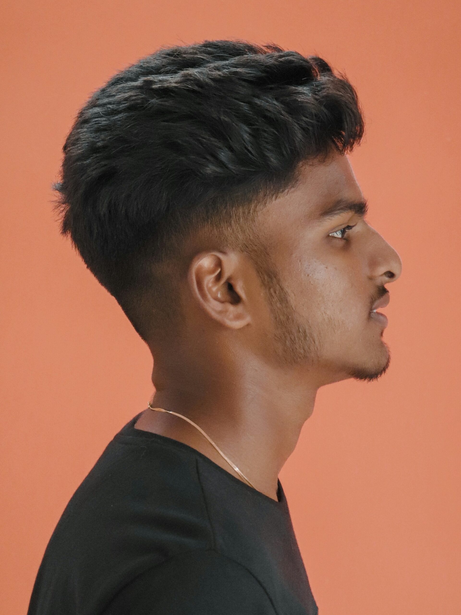 Zijaanzicht van een man met een getextureerd volumekapsel gecombineerd met een low taper fade