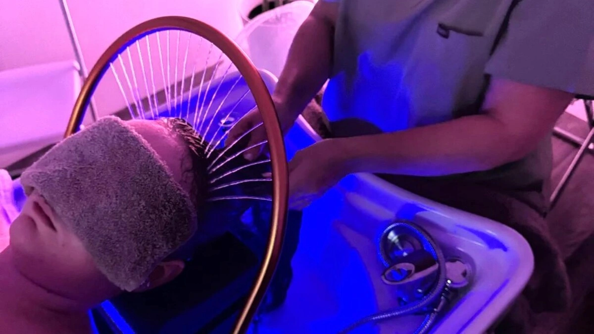 Bovenaanzicht van een behandelaar die het haar van een klant wast tijdens een Japanese head spa-behandeling