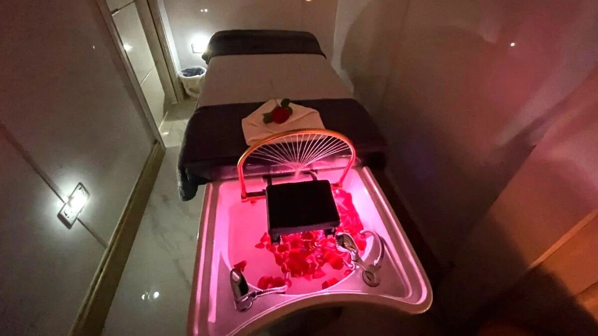 Binnenkijken in een rustgevende Japanese head spa-behandelruimte met gedempt licht, met een behandeltafel, een wasbak met bloemblaadjes en spa-apparatuur