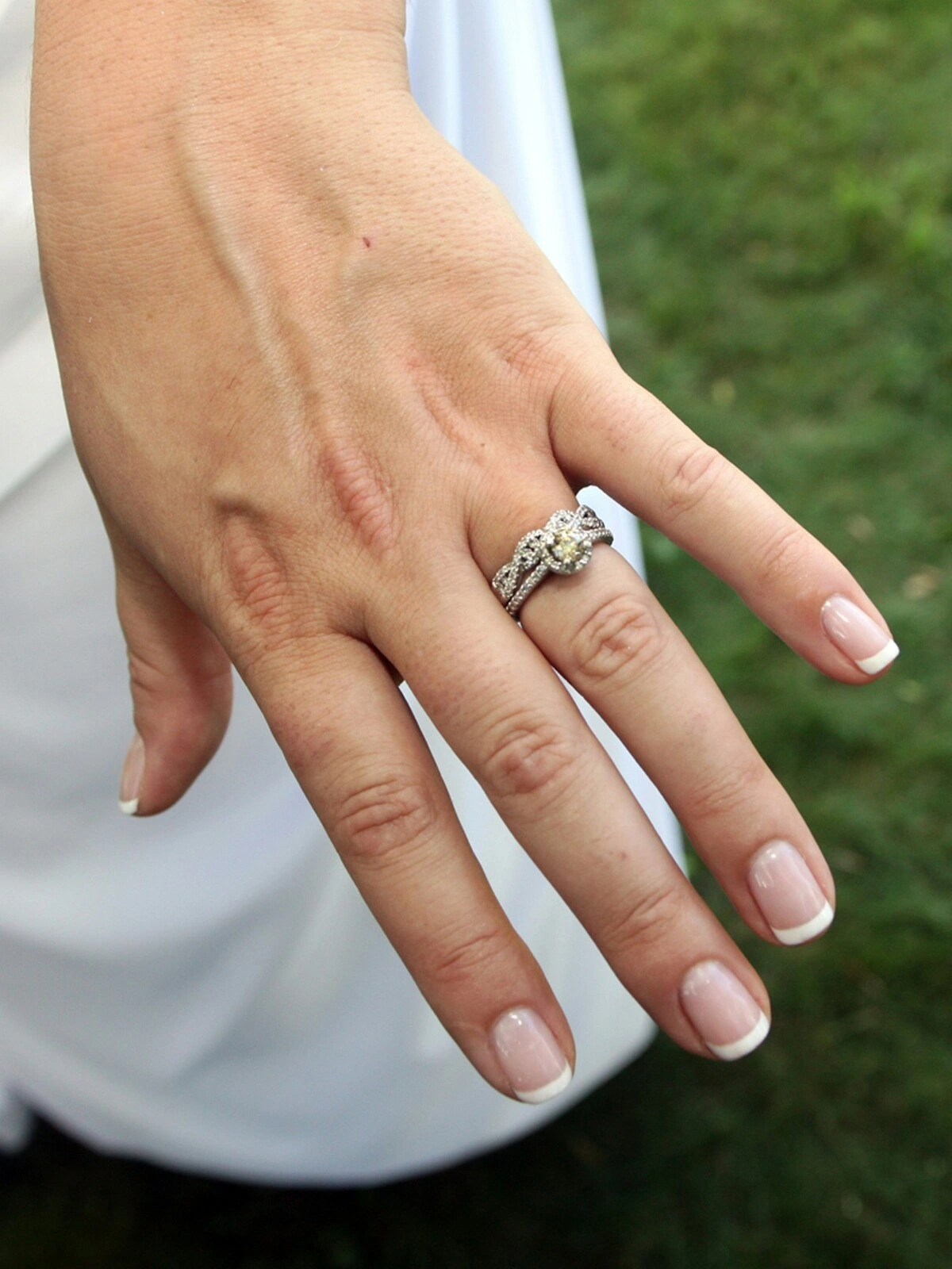 De hand van een vrouw met een verzorgde French manicure in een klassieke combinatie van nude en wit op korte, vierkant-ovale nagels