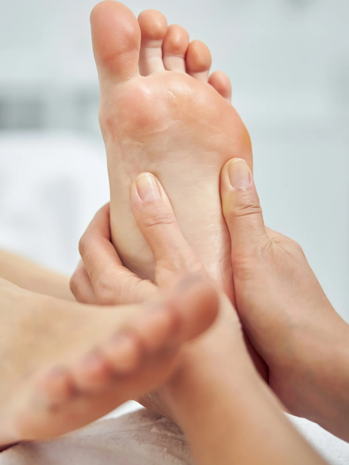 Close-up van een specialist die tijdens een droge pedicure de voet van een klant masseert