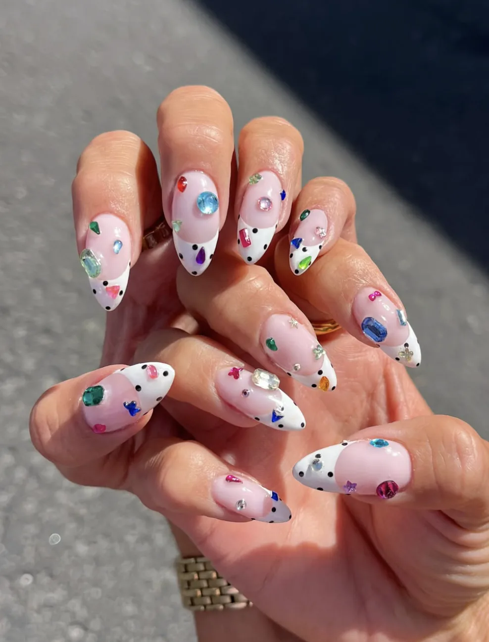 Amandelvormige bedazzled-nagels met kleurrijke strasssteentjes en witte tips met stippen